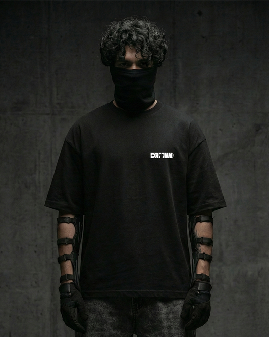 Person wearing a black t-shirt with drivn logo, black gloves, and a black balaclava against a dark background