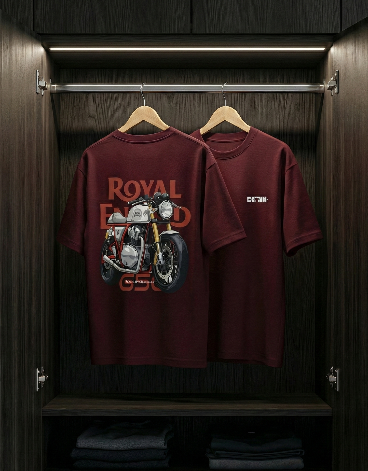 Two maroon t-shirts with motorcycle graphics hanging in a wooden wardrobe.