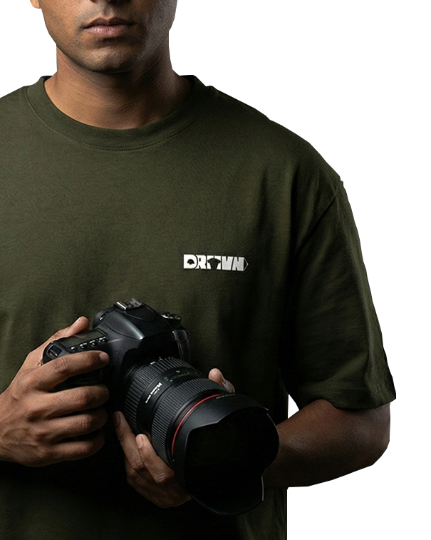 Man holding a camera wearing an olive green drivnwear tshirt