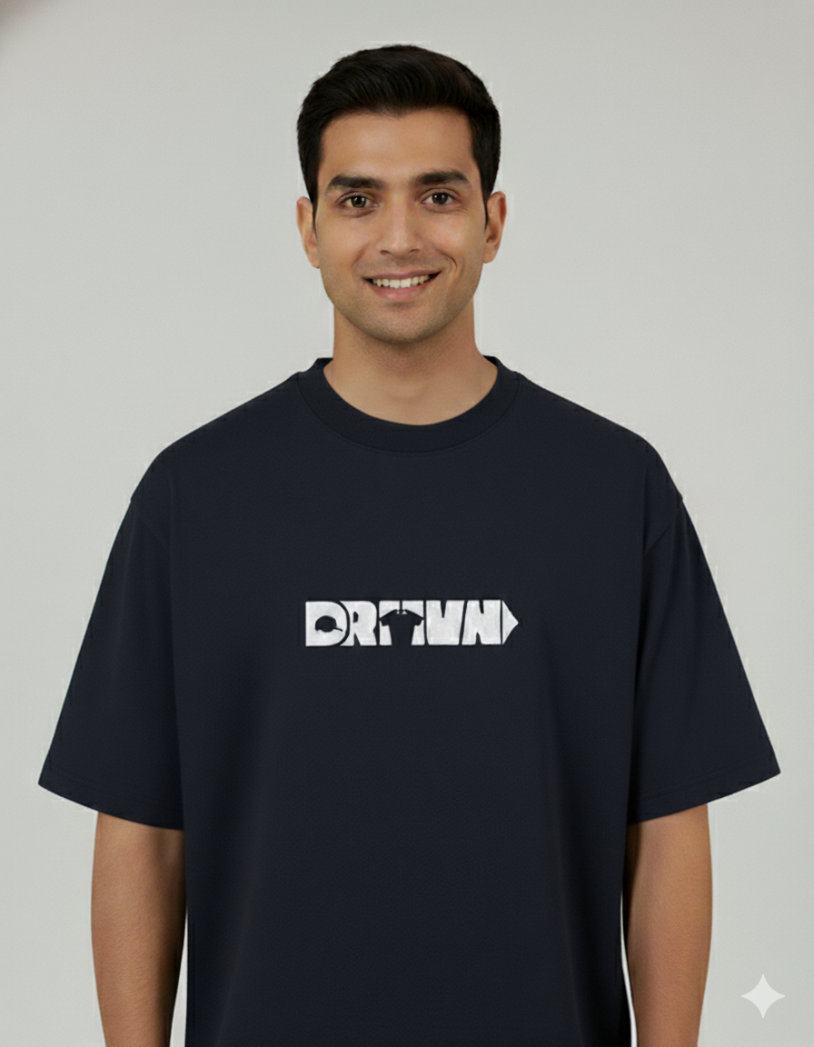 Man wearing a black t-shirt with a logo of drivn on a gray background