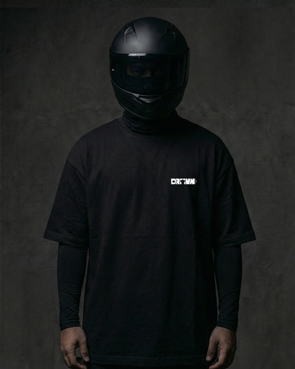 Person wearing a black helmet and black t-shirt with drivnwear logo on a dark background