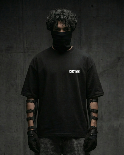 Person wearing a black t-shirt with drivn logo, black gloves, and a black balaclava against a dark background
