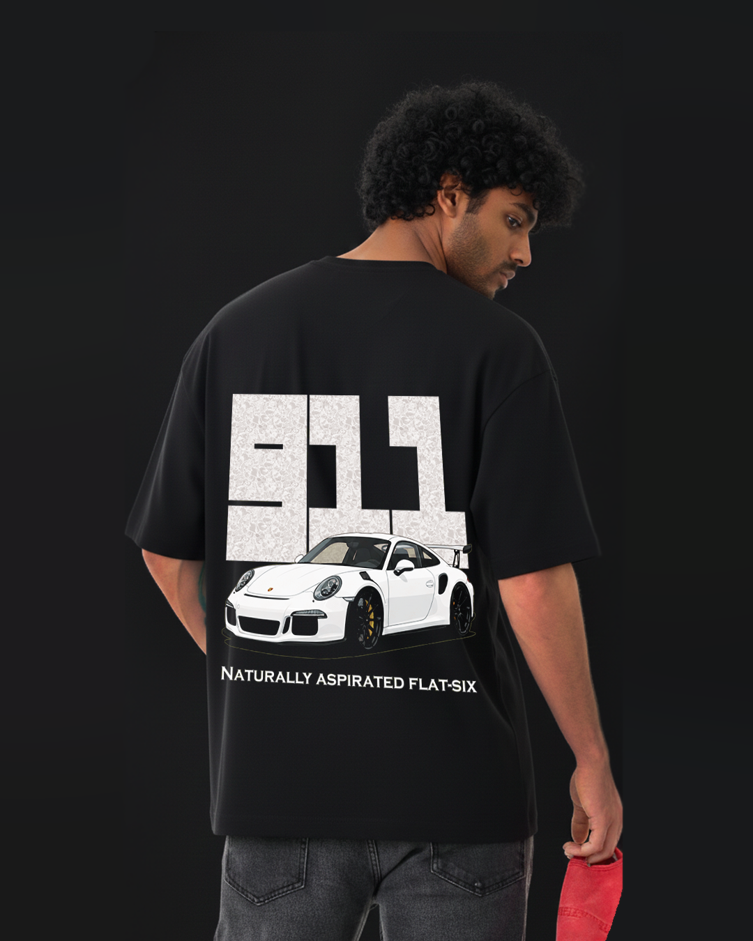 Person wearing a black t-shirt with a porsche 911 car graphic and text on the back against a black background